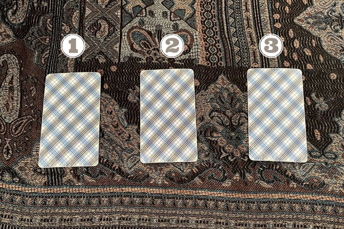 Tres cartas del Tarot ocultas encima de una tela.