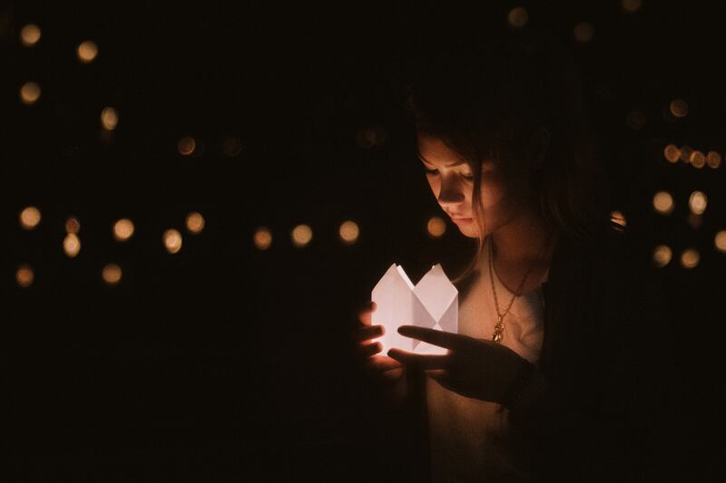 Mujer observando una linterna de papel en sus manos.