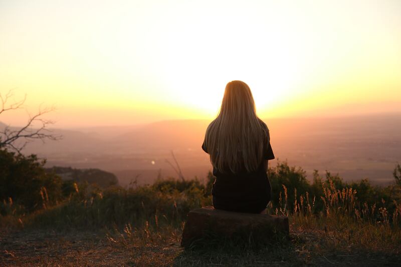 Mujer de espalda viendo la puesta del sol.