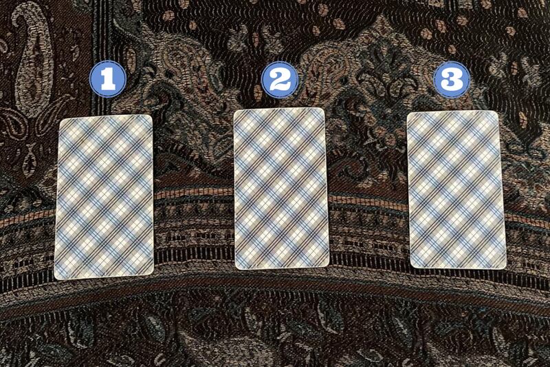 Tres cartas del Tarot ocultas sobre una tela.