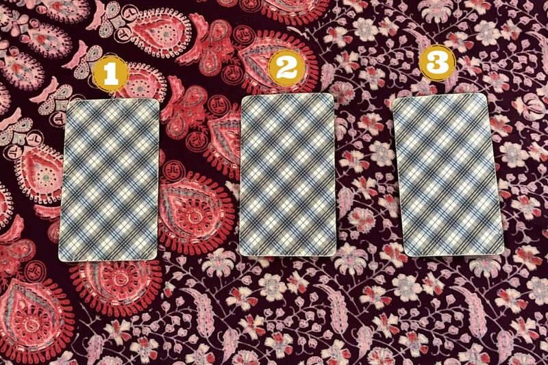 Tres cartas del Tarot sin revelar sobre una tela.