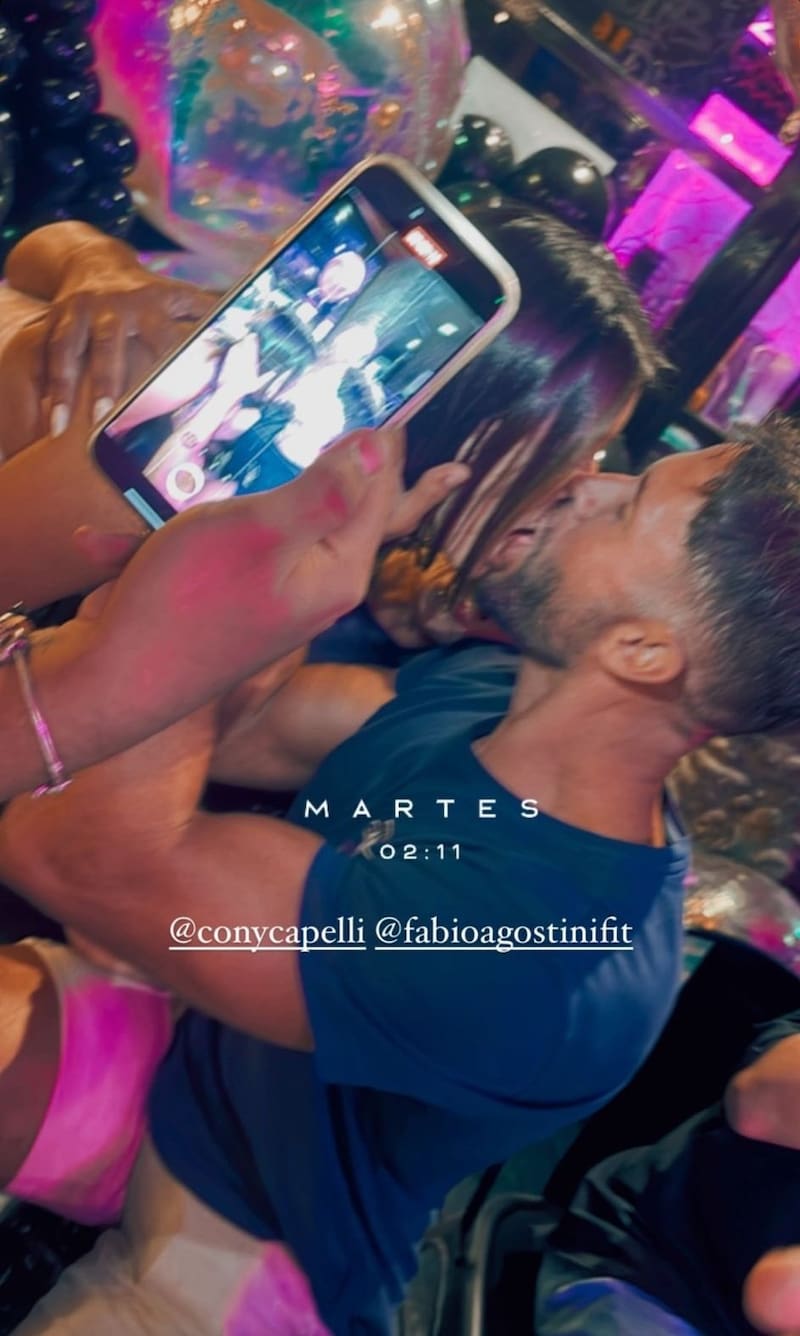 Constanza Capelli y Fabio Agostini besándose en celebración de cumpleaños.