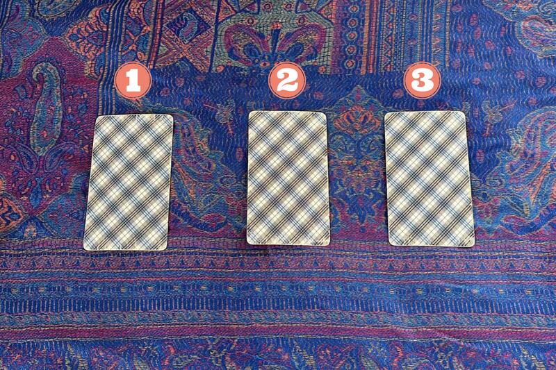 Tres cartas del Tarot ocultas sobre una tela.