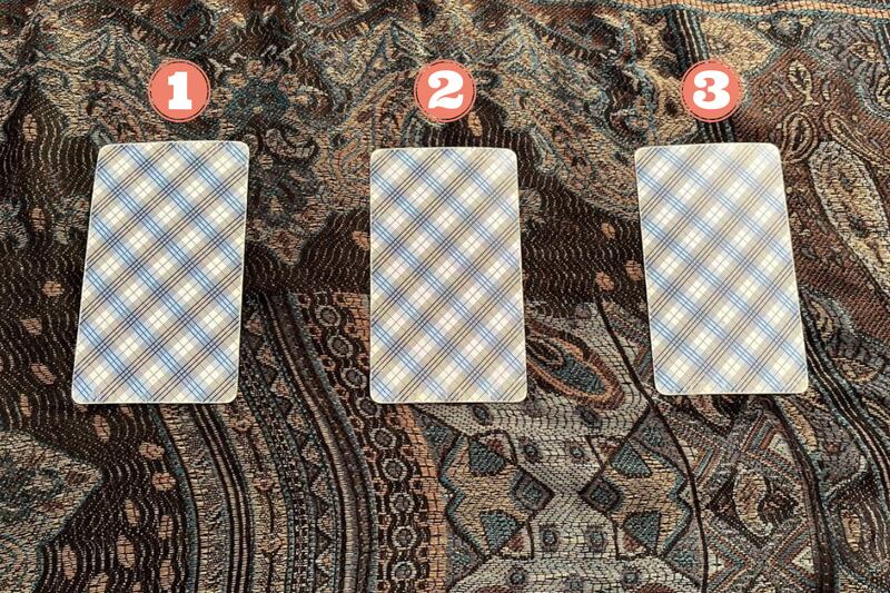 Tres cartas del Tarot al revés sobre un mantel