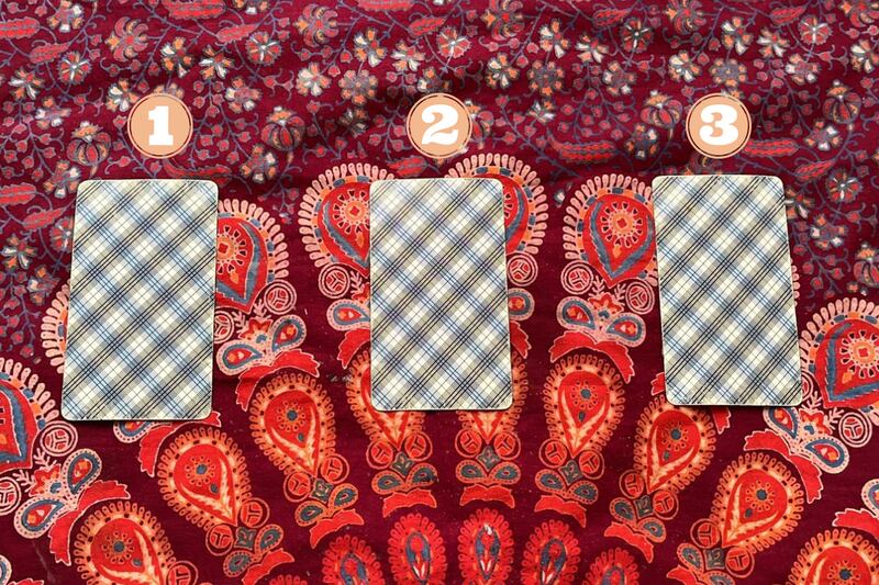 Tres cartas del Tarot ocultas sobre una tela.