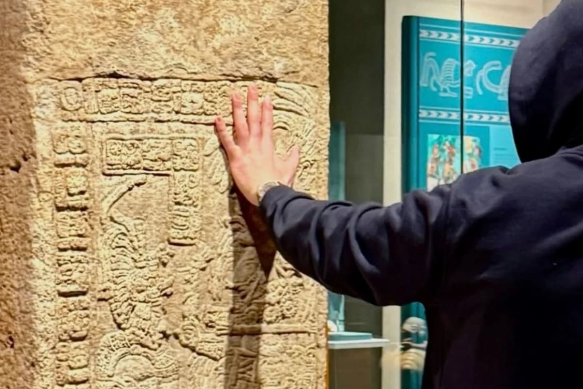 El artista tocando la piedra arqueológica en el Museo Nacional de Antropología.
