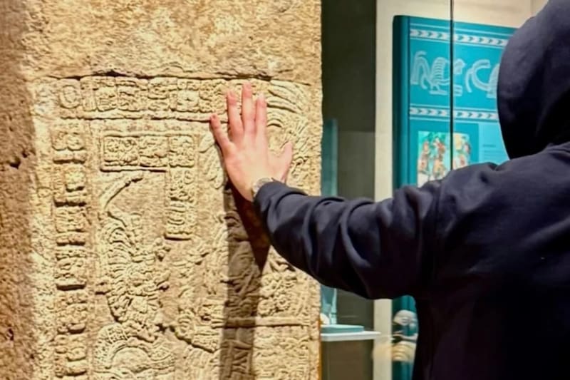El artista tocando la piedra arqueológica en el Museo Nacional de Antropología.